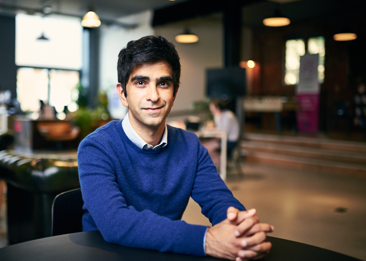 Portrait of Zeeshan Akhtar, CEO and found of Scout Health, sitting at a cafe table.