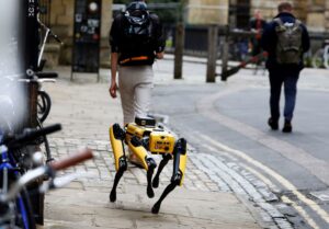 Yellow '4-legged' dog robot walking on pavement in Oxford