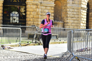 Runner running between barricades of marathon, with buildings in background