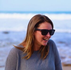 Woman with long brown hair with seascape background behind