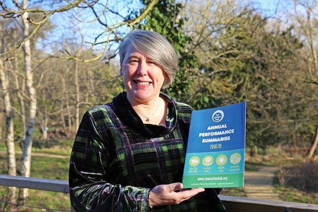 Portrait of Barbara Hammond from Low Carbon Hub stands outside the Wood Centre for Innovation and holds a copy of a report.