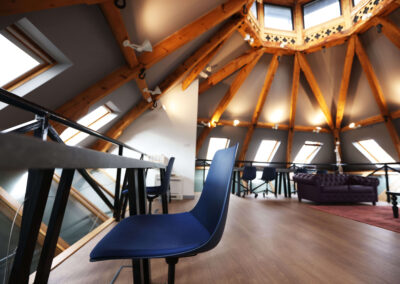 An interior shot of the Oxford Centre for Innovation showing the wooden beam roof, plus desks and chairs.