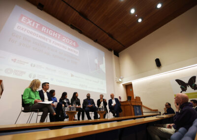 Panellists at the Exit Right event sit on a stage with a large screen behind facing the audience.
