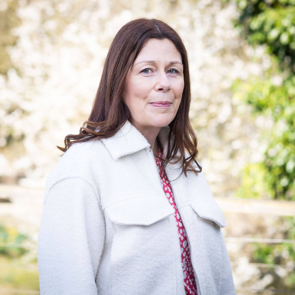 A member of The Oxford Trust stands outside the Wood Centre for Innovation's deck, with trees in the background.