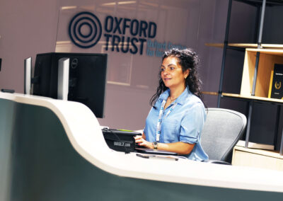 The Assistant Centre Manager sits at the reception working at a computer and screen at the Oxford Centre for Innovation.