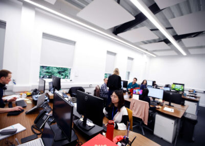 An open-plan office with team members sitting and working at desks and computers.
