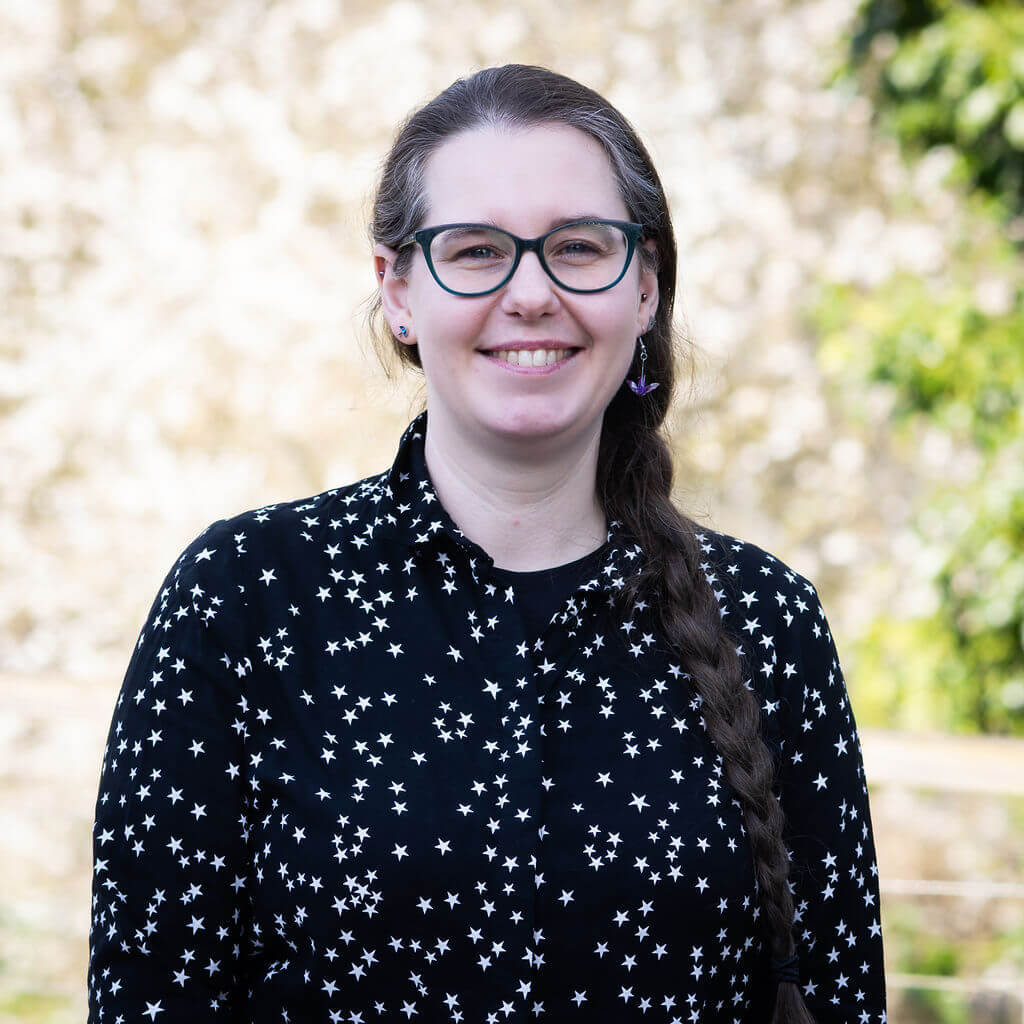 A member of The Oxford Trust stands outside the Wood Centre for Innovation's deck, with trees in the background.