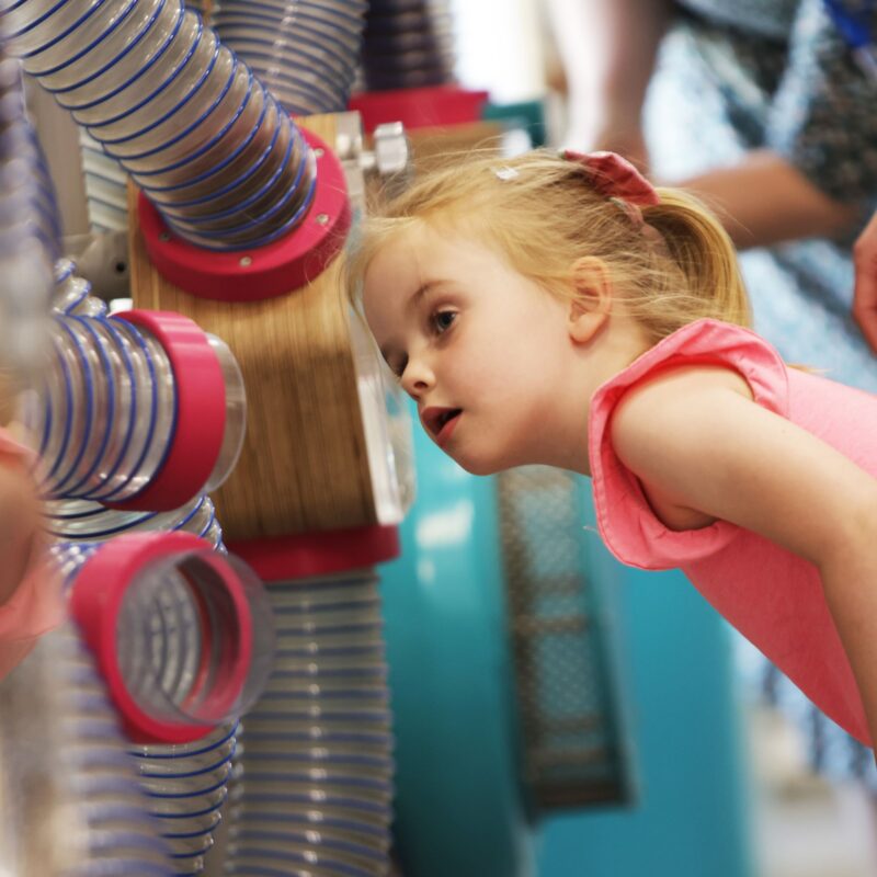 A young girl looks into a tube
