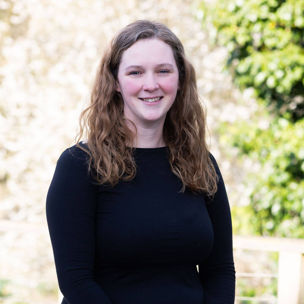 A member of The Oxford Trust stands outside the Wood Centre for Innovation's deck, with trees in the background.