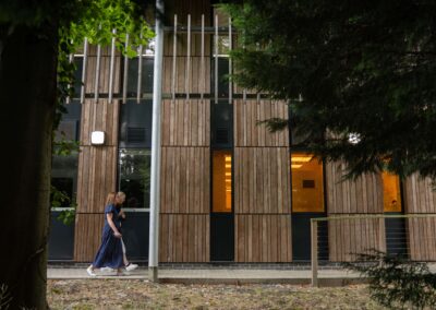 People walking outside the Wood Centre for Innovation past the mature trees.