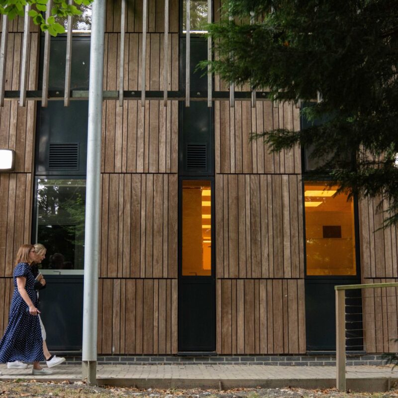People walking outside the Wood Centre for Innovation past the mature trees.