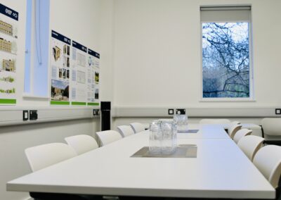 The boardroom at the Wood Centre for Innovation showing a white table, with white chairs and glasses set on the table..