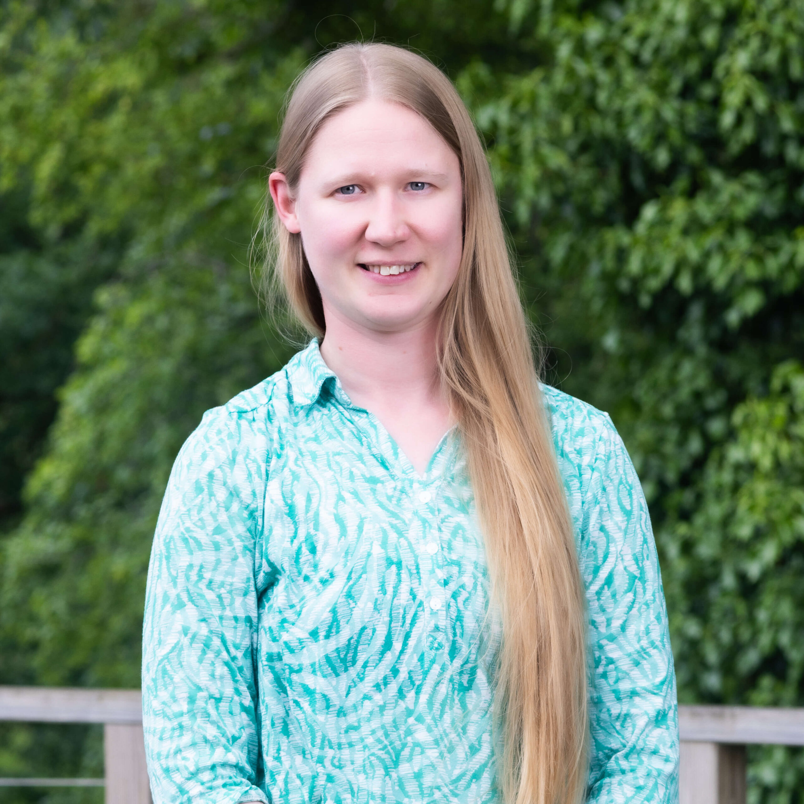 A member of The Oxford Trust stands outside the Wood Centre for Innovation's deck, with trees in the background.