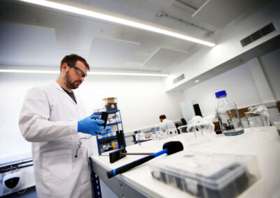 A person wearing a lab coat and glasses experiments in their technical workspace at the Wood Centre for Innovation.